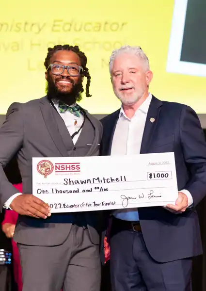 Shawn Mitchel carrying a large check for $10,000