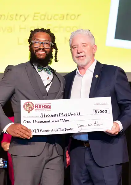 Shawn Mitchel carrying a large check for $10,000