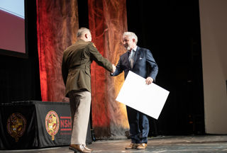 A man shaking another man's hand on stage