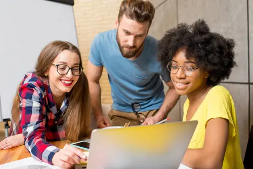 A group of students looking at a computer screen smiling