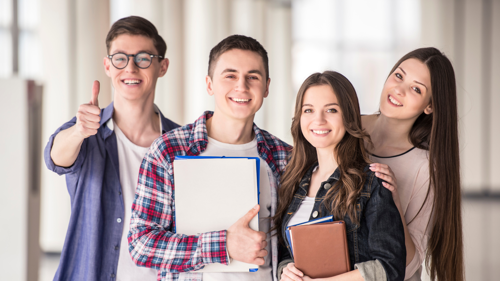 A group of students standing in a corridor and smiling to the camera