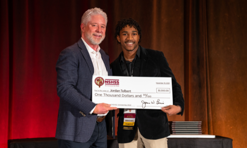 Happy scholarship recipient is holding a large check