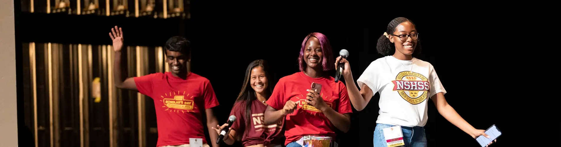 Group of diverse volunteers smiling and waving on stage