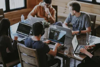Group of students sitting around laptops at a table