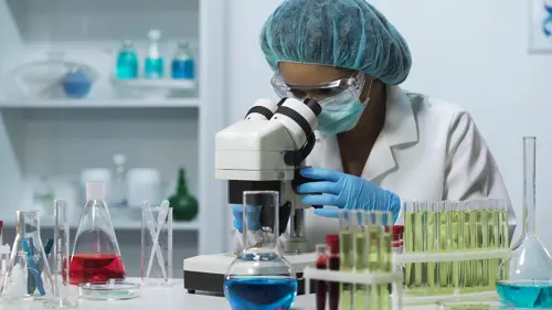 A woman studying reactants through a microscope