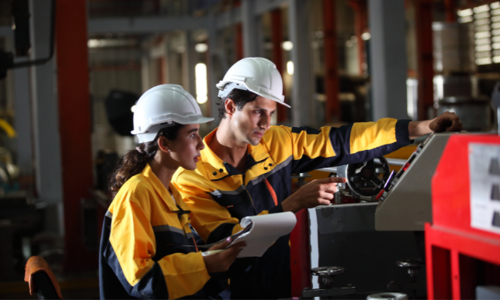 Two industrial engineers checking a machine dashboard in a workshop